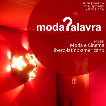 Capa da Modapalavra, V.12, N.25 (2019). Ambiente iluminado por luz vermelha e luminária. No canto superior direito, círculo vermelho com o logotipo da revista Modapalavra com um ponto de interrogação estilizado como letra p e o título do dossiê Dossiê Moda e Cinema Ibero-Latino-Americano.